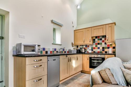 a kitchen with wooden cabinets and a microwave at No 1 The Granary in Llangefni