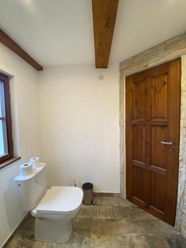 a bathroom with a toilet and a wooden door at Chaloupka Stanětice in Zahořany