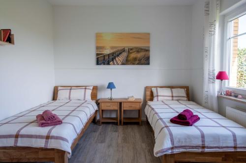 2 Betten in einem Zimmer mit rosa Handtüchern darauf in der Unterkunft FH Ostfriesland to Huus, zw. Emden und Greetsiel in Hinte