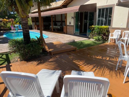 un patio con sillas blancas y una piscina en Casa nas montanhas com piscina e vista panorâmica en Domingos Martins