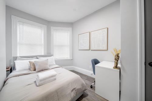 a white bedroom with a bed and a chair at 4BR 1BH Apt in South Boston near Old Harbor Beach Private Rooms in Boston