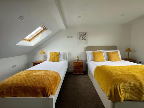 two beds in a room with yellow pillows at Luxurious 5 Bedroom Parking EV Great Location in Morecambe
