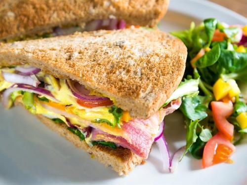 uma sanduíche e uma salada num prato branco em Parkside Hotel em Cleator
