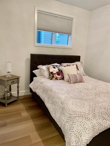 a bed with pillows and a window in a bedroom at Adorable 1 Bedroom Suite- a skip to Galloping Goose in Victoria