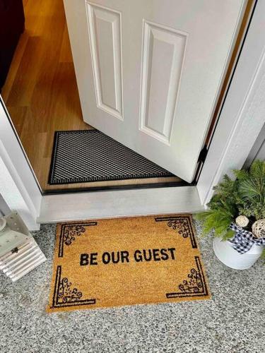 a door mat with a sign that reads be our guest at Adorable 1 Bedroom Suite- a skip to Galloping Goose in Victoria