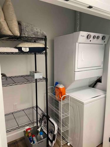 a laundry room with a washing machine and a shelf at Adorable 1 Bedroom Suite- a skip to Galloping Goose in Victoria