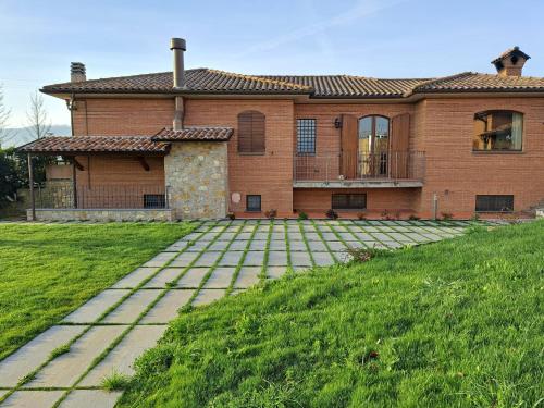 a large brick house with a walkway in front of it at Agriturismo A Casa Mia Gubbio in Gubbio