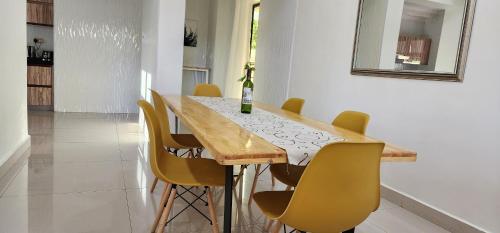 a dining room table with yellow chairs and a bottle of wine at InstaHomes by Tru - Villa in Blantyre