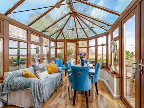 a conservatory with a couch and a table and chairs at Brittons Hill Cottage in Wavehorne