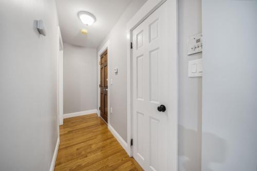 a hallway with a white door and wooden floors at 4BR1BTH South Boston Apt perfect for commutes in Boston