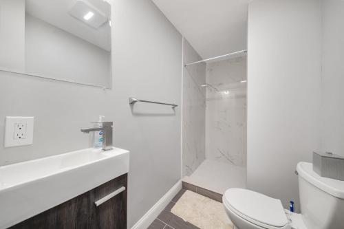 La salle de bains blanche est pourvue d'une douche et de toilettes. dans l'établissement 4BR1BTH South Boston Apt perfect for commutes, à Boston