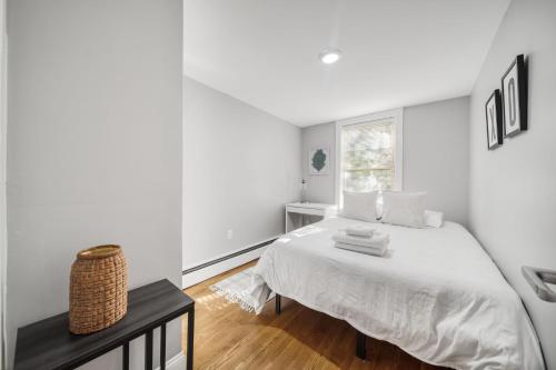 um quarto branco com uma cama e uma janela em 4BR1BTH South Boston Apt perfect for commutes em Boston