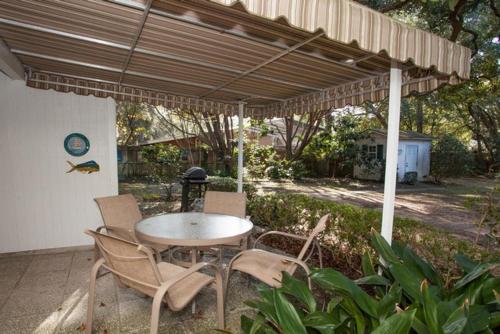 a patio with a table and chairs under an umbrella at PELICAN HOUSE home in Jekyll Island