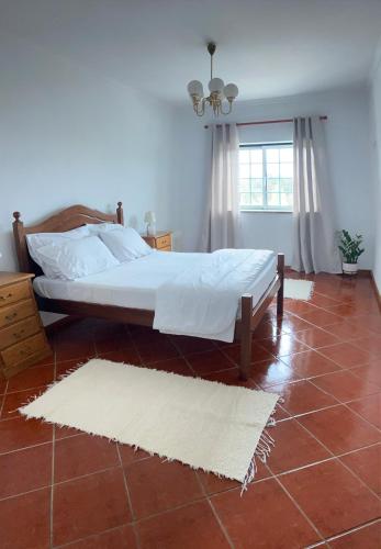 ein Schlafzimmer mit einem Bett und einem roten Fliesenboden in der Unterkunft MaJô Alojamento Local in Tábua