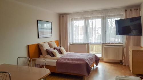 um quarto com uma cama com almofadas e uma televisão em Apartamenty Agat i Jantar em Świnoujście