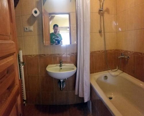 a man taking a picture of a bathroom with a sink and tub at Salas-Partizanske in Partizánske