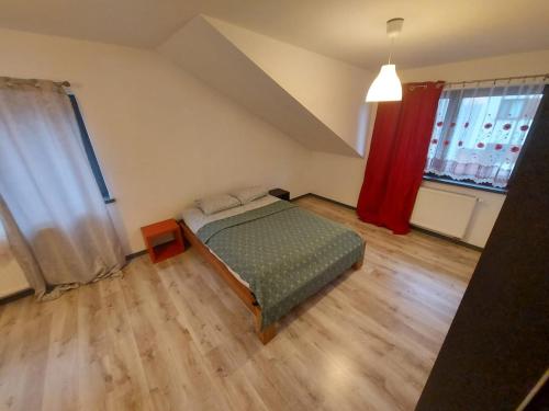sypialnia z łóżkiem i czerwoną zasłoną w obiekcie Galeria Kolorów pokój rodzinny w Łodzi
