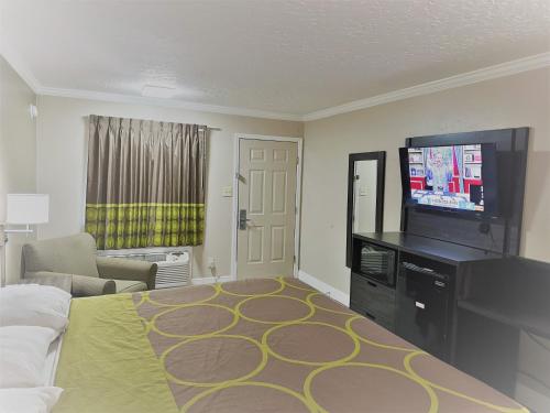 a living room with a bed and a flat screen tv at Super 8 by Wyndham Picayune in Picayune