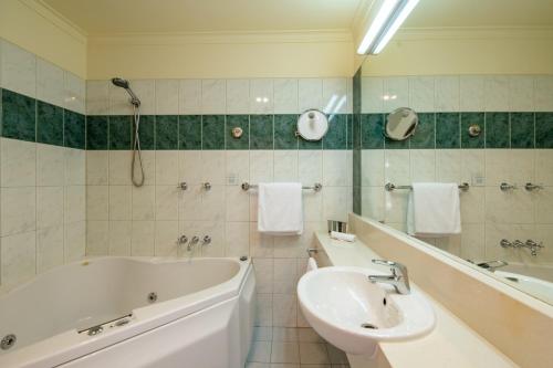 a white bathroom with a tub and a sink at Gateway on Monash in Clayton North