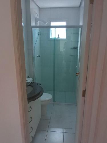 La salle de bains est pourvue d'une douche en verre et de toilettes. dans l'établissement Mar, Praia, Sossego e Tranquilidade, à Itanhaém