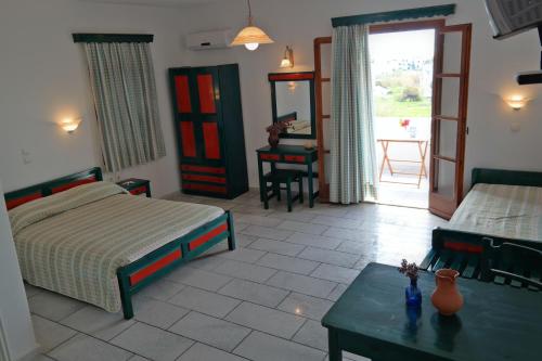 a bedroom with two beds and a table and a door at Dina's Diamond in Agios Prokopios