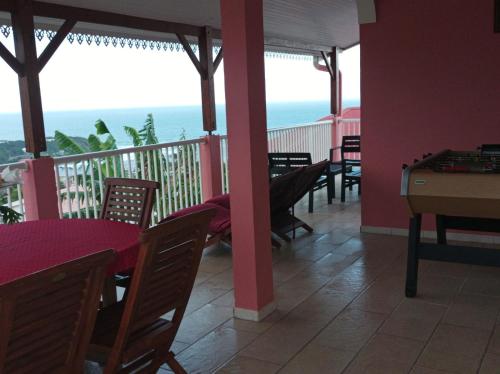 a restaurant with tables and chairs and a balcony with the ocean at VILLA C'MARGOT in Marigot