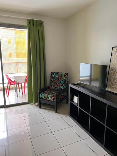 ein Wohnzimmer mit einem TV und einem Stuhl in der Unterkunft Studio Temanea in Papeete