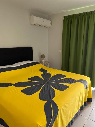 ein Schlafzimmer mit einem gelben Bett und grünen Vorhängen in der Unterkunft Studio Temanea in Papeete