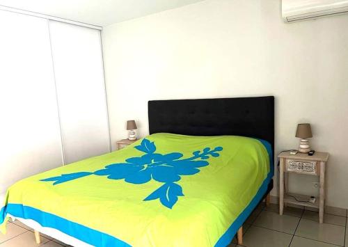 ein Bett mit einer grünen Decke mit blauen Blumen drauf in der Unterkunft Studio Temanea in Papeete