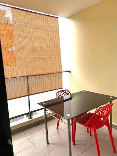 einen schwarzen Tisch und zwei rote Stühle vor einem Fenster in der Unterkunft Studio Temanea in Papeete