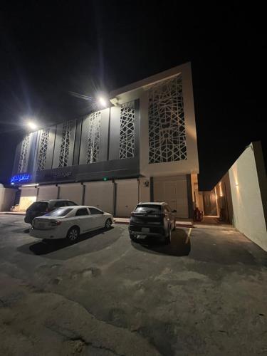 two cars parked in front of a building at night at شقة حديثه حي النرجس تسجيل ذاتي in Riyadh