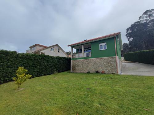 a house with a green wall and a yard at Casa as Milleiras - Serantes - Laxe in Laxe