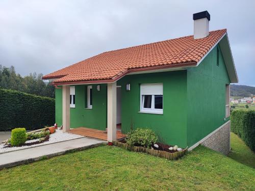 una casa verde con techo rojo en un patio en Casa as Milleiras - Serantes - Laxe, en Laxe