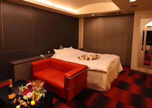 a hotel room with a bed and a red chair at 福井・鯖江のホテル｜ホテルモーメント in Sabae