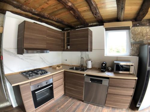 uma cozinha com armários de madeira e um forno com placa de fogão em Vila Espigueiro I em Bustelo