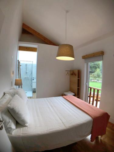 a bedroom with a large white bed and a window at Vila Forno in Bustelo