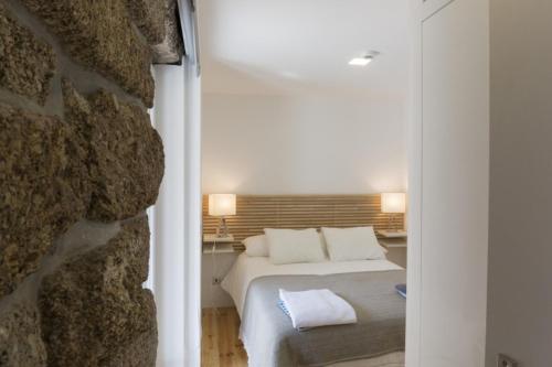 a bedroom with a bed next to a stone wall at Vila Lagar in Bustelo