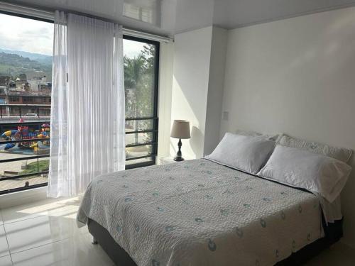 - une chambre blanche avec un lit et une grande fenêtre dans l'établissement Magnifico apartamento, à Moniquirá