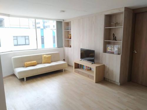 a living room with a white couch and a tv at Acogedor Apartamento in Quito