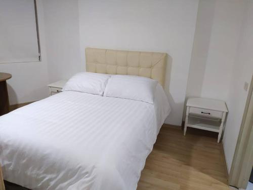 1 dormitorio con cama blanca y mesita de noche en Acogedor Apartamento, en Quito