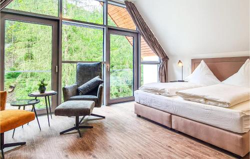 een slaapkamer met een bed, een stoel en ramen bij Stunning Home In Lautenthal With Kitchen in Lautenthal