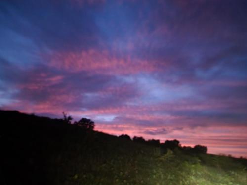 una puesta de sol en la cima de una colina con un cielo en Goin' Bonanza Glamping Ranch, en Hardy
