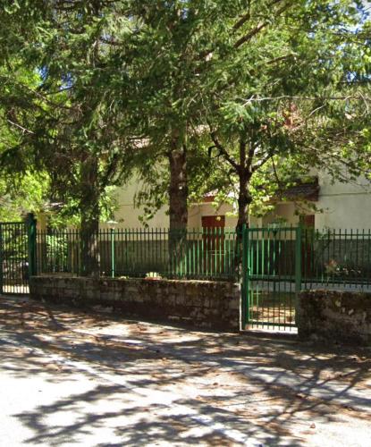 uma cerca verde em frente a uma casa com árvores em White’s House em Cutura