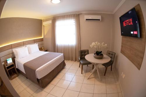 a hotel room with a bed and a small table at Hotel Capital Das Pedras in Teófilo Otoni