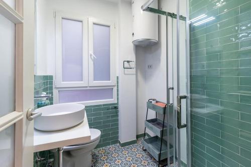 a bathroom with a sink and a toilet and green tiles at Piso céntrico San Simón in Santander