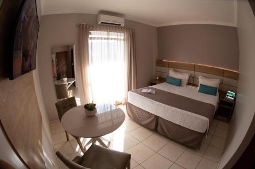 a hotel room with a bed and a table with a table at Hotel Capital Das Pedras in Teófilo Otoni