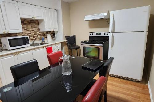 a kitchen with a black table and a white refrigerator at Chesskings Guest House - Unit 2 in Winnipeg