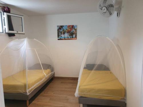 2 camas en una habitación con tienda de campaña en Appartement neuf et tout confort sur la Trinité, en La Trinité