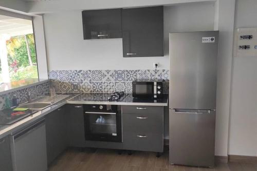 una cocina con electrodomésticos de acero inoxidable y armarios negros en Appartement neuf et tout confort sur la Trinité, en La Trinité