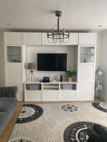 a living room with a white entertainment center with a flat screen tv at Hameway House- Stunning 4 bedroom house with a spacious kitchen in London